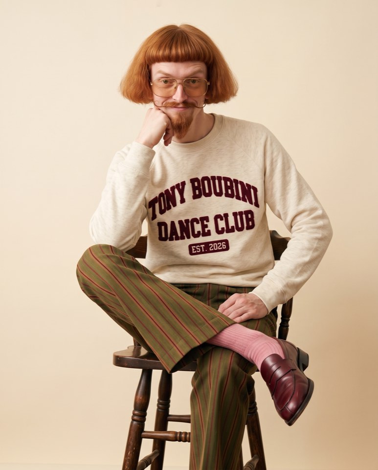 Tony sitting on a stool in the Dance Club sweater